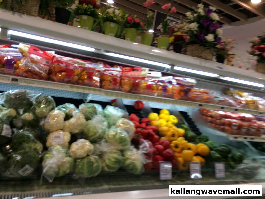 A vibrant display of fresh vegetables, including bell peppers and leafy greens, in a supermarket produce section.
