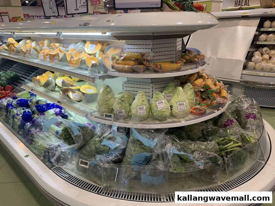 A refrigerated display of fresh produce including pumpkins, corn, and various leafy greens in a supermarket.