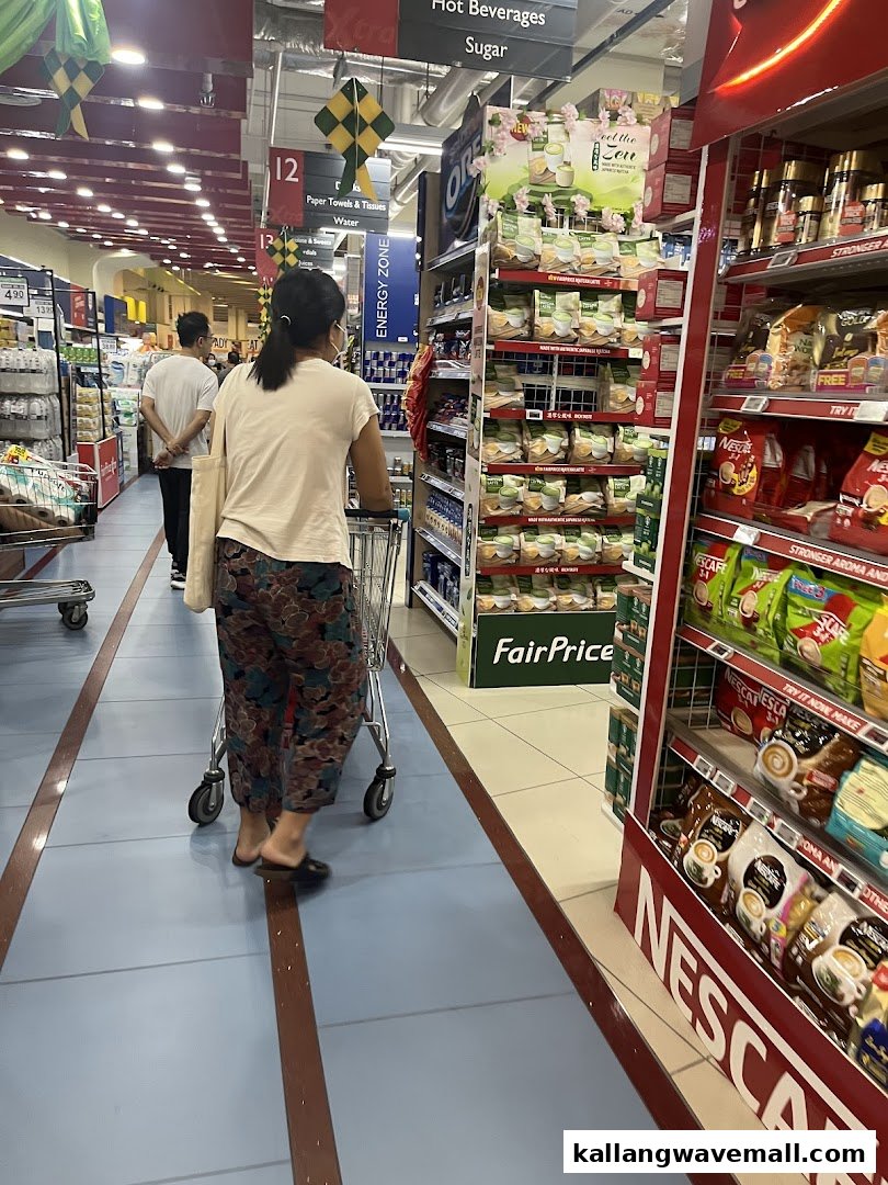A shopper pushes a cart down a well-stocked aisle in FairPrice Xtra supermarket.