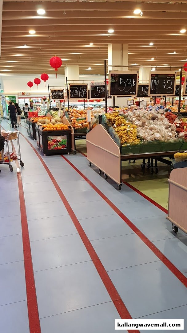 An aisle in FairPrice Xtra Sports Hub supermarket, featuring fresh produce displays and festive red lanterns.