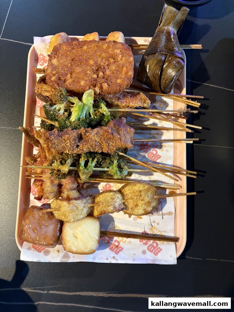 A tray filled with various fried and skewered food items, including vegetables, hash brown, and a wrapped dumpling.