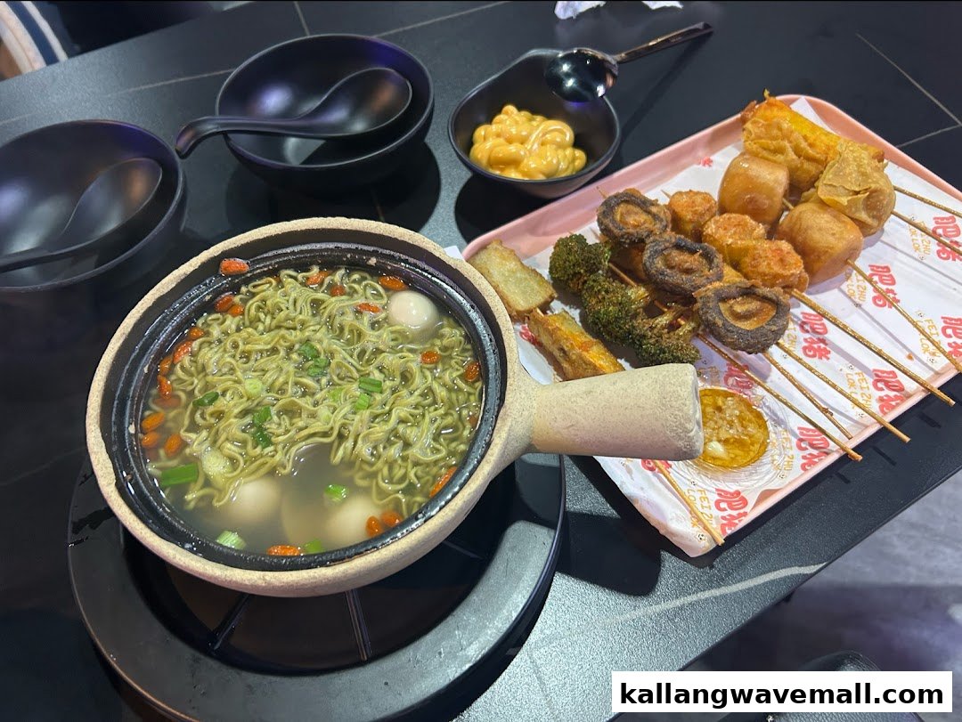 A claypot of green noodles with fish balls and a platter of assorted fried skewers and dipping sauce.