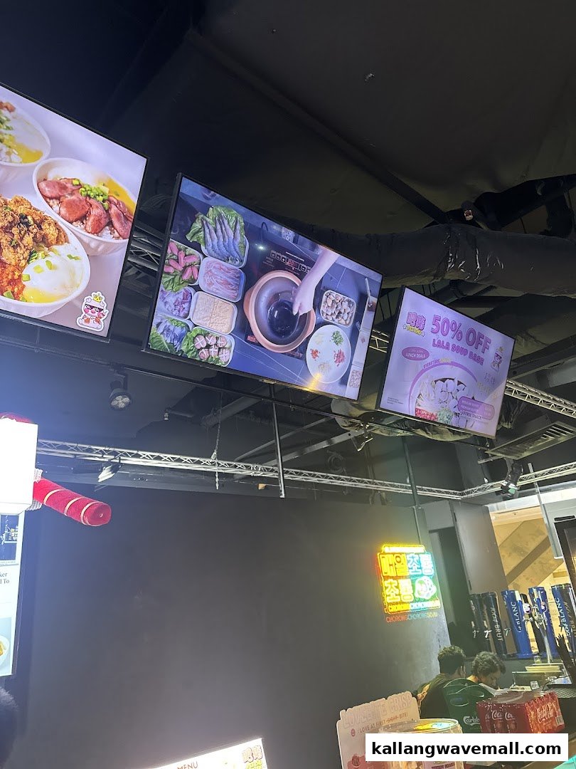 Interior view of Fei Zhu Lok Lok restaurant, featuring digital screens displaying hotpot ingredients and promotions.