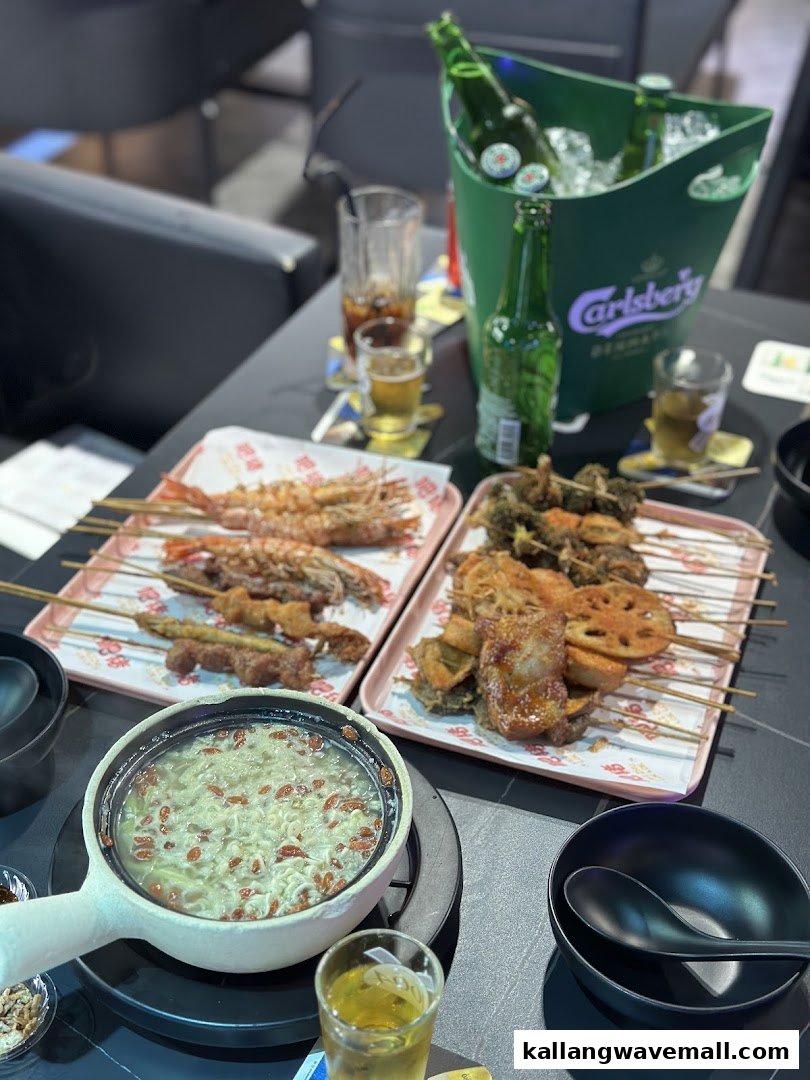 A table laden with various skewers, a hotpot, and a bucket of beer, ready for a meal.