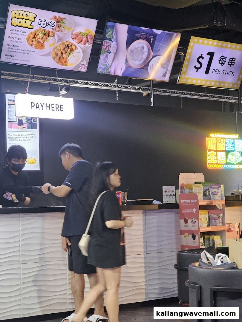 Customers at a counter with digital menu boards displaying food items and prices.