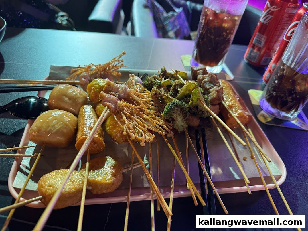 A tray of assorted skewered food (Lok Lok) and drinks on a table in a restaurant setting.