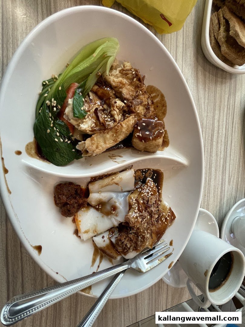 A delicious plate featuring yong tau foo style items with vegetables, tofu, and rice rolls, served with sauce.