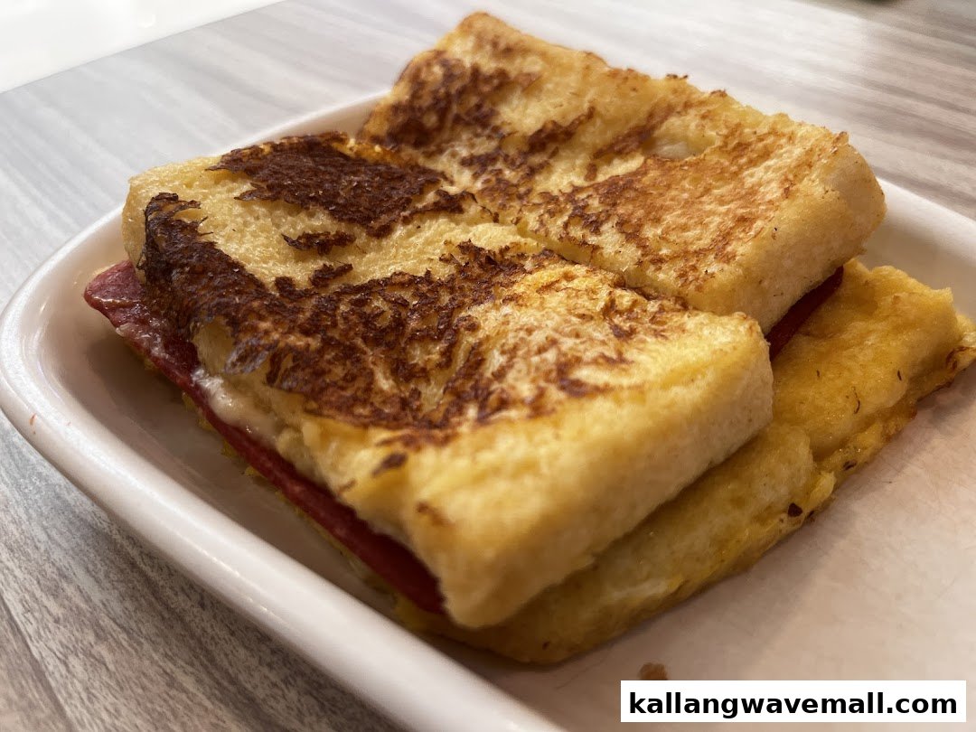 A close-up of a golden-brown French toast sandwich with a savory filling on a white plate.