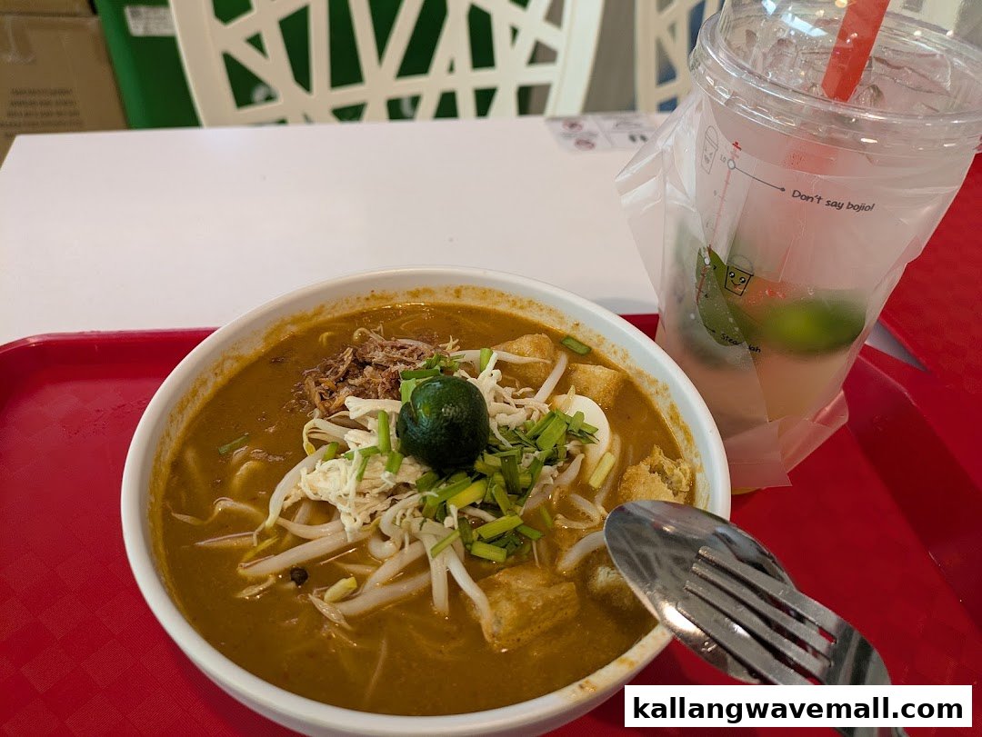 A delicious bowl of curry noodles with toppings and a refreshing drink on a red tray.