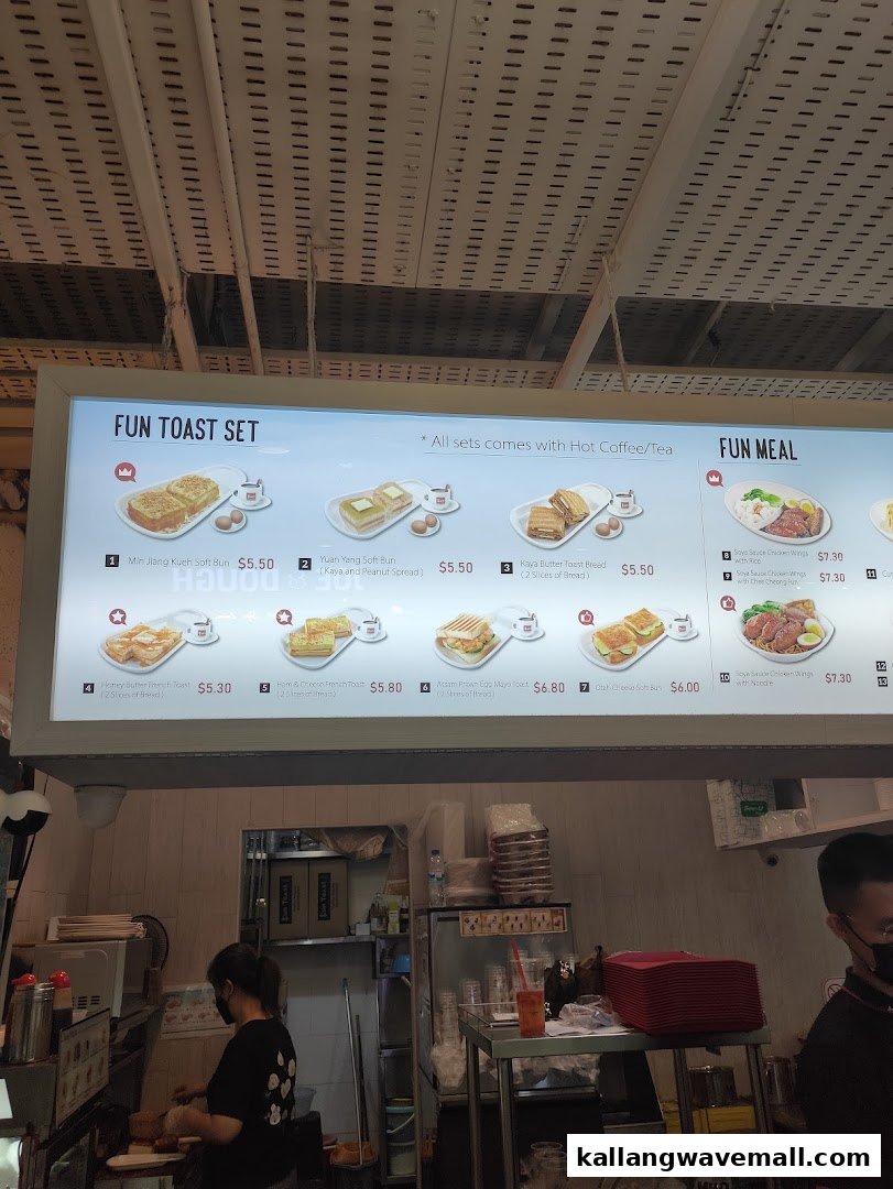 A brightly lit menu board displaying toast sets and fun meals, with a glimpse of the kitchen area below.