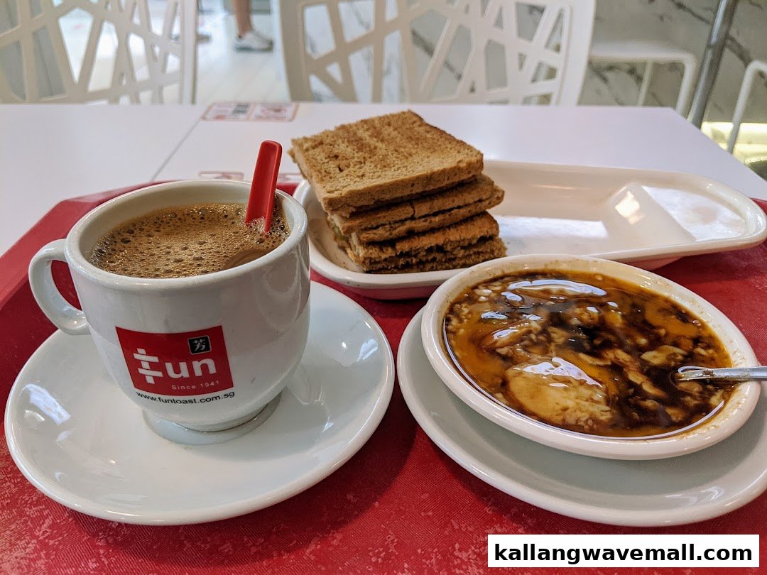 A traditional Singaporean breakfast set featuring kopi, kaya toast, and soft-boiled eggs on a red tray.