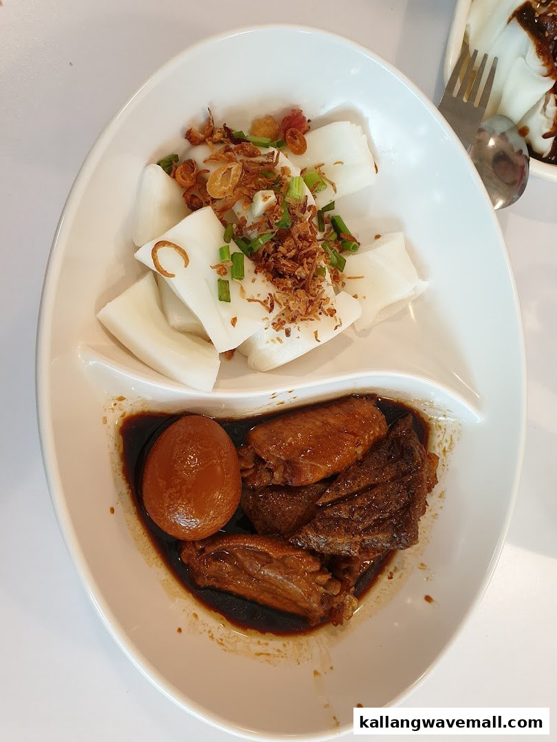 A delicious plate featuring rice rolls topped with fried shallots and braised chicken wings with an egg.