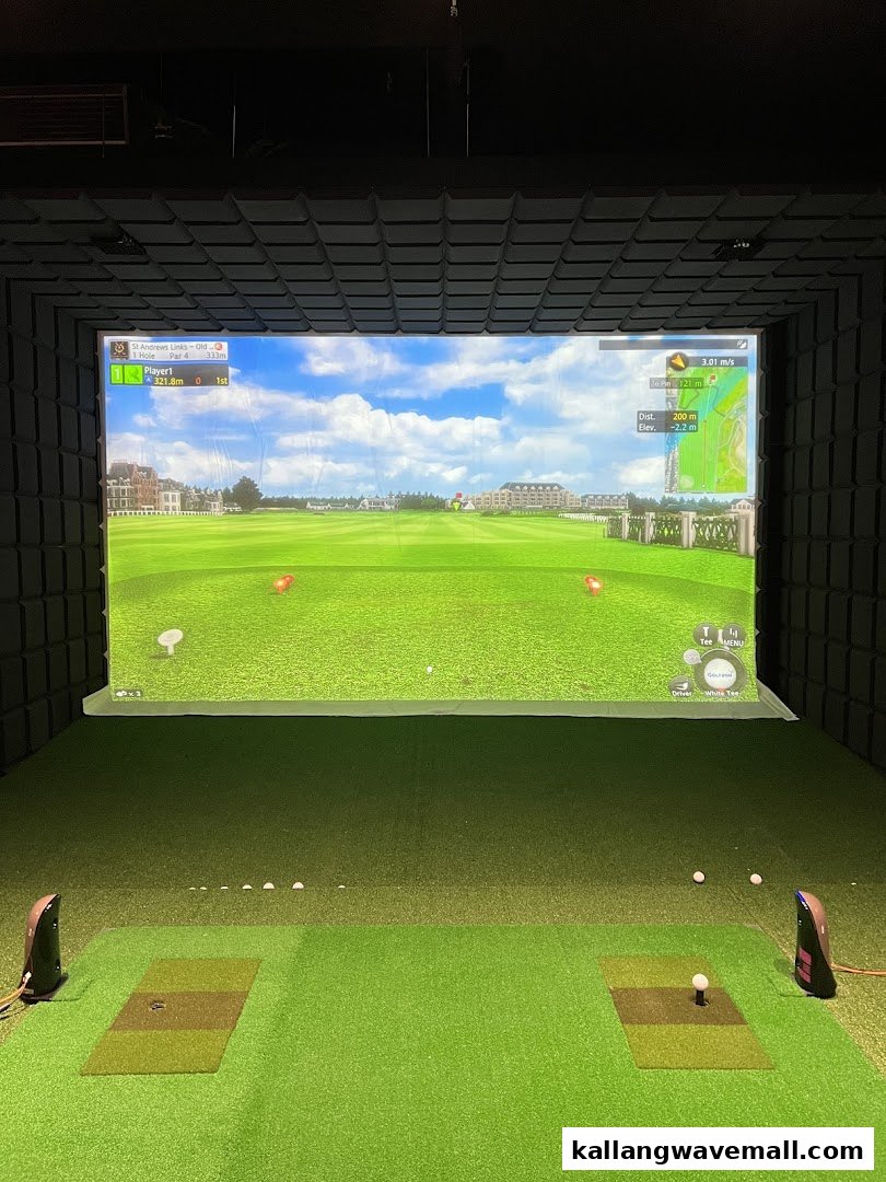 An indoor golf simulator bay with a large screen displaying a virtual golf course.