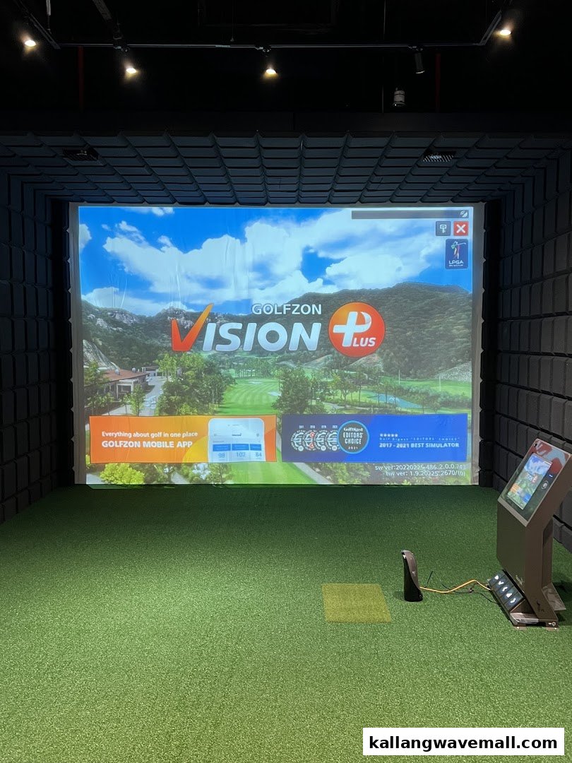 An indoor golf simulator bay with a large projection screen and artificial turf.
