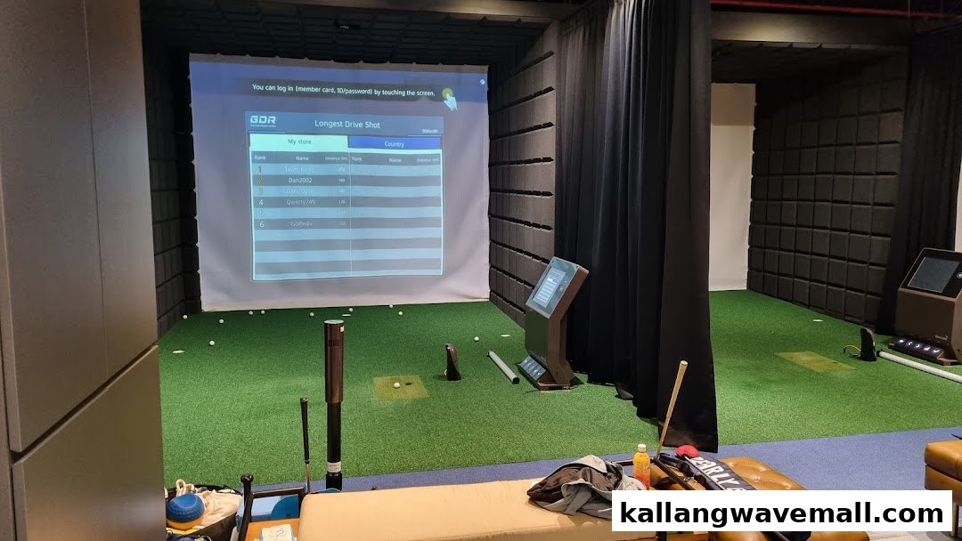 An indoor golf simulator bay with a large projection screen and golf equipment.