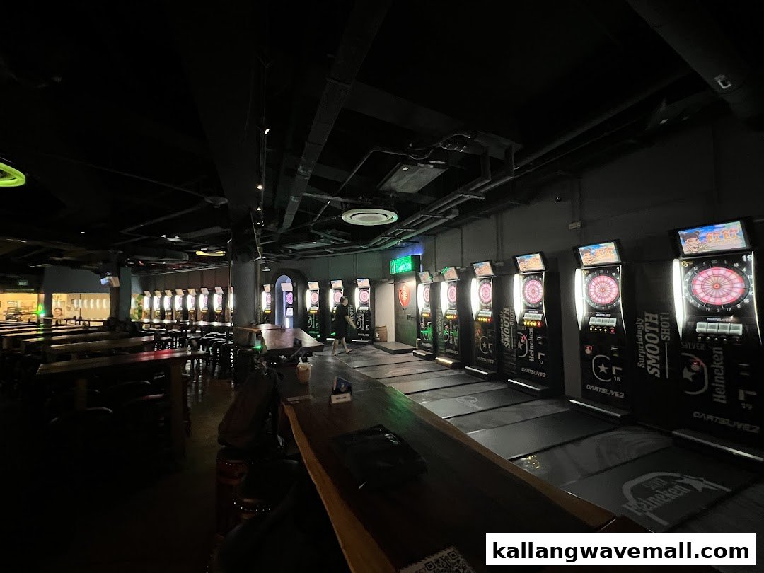 An interior view of a dimly lit dart bar with multiple electronic dart machines and seating areas.