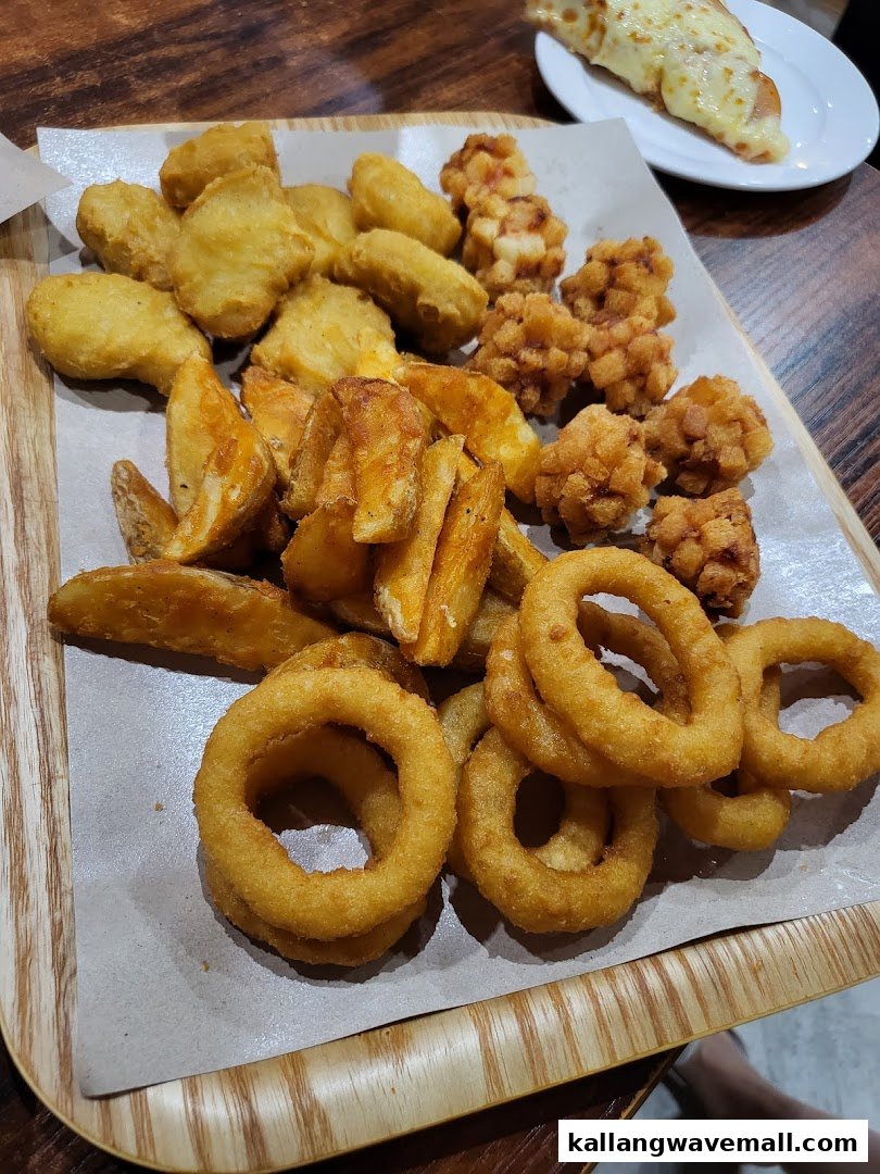 A platter of golden fried chicken nuggets, potato wedges, onion rings, and a cheesy breadstick.