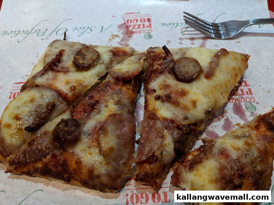 Close-up of several slices of pizza with sausage and cheese on branded paper.
