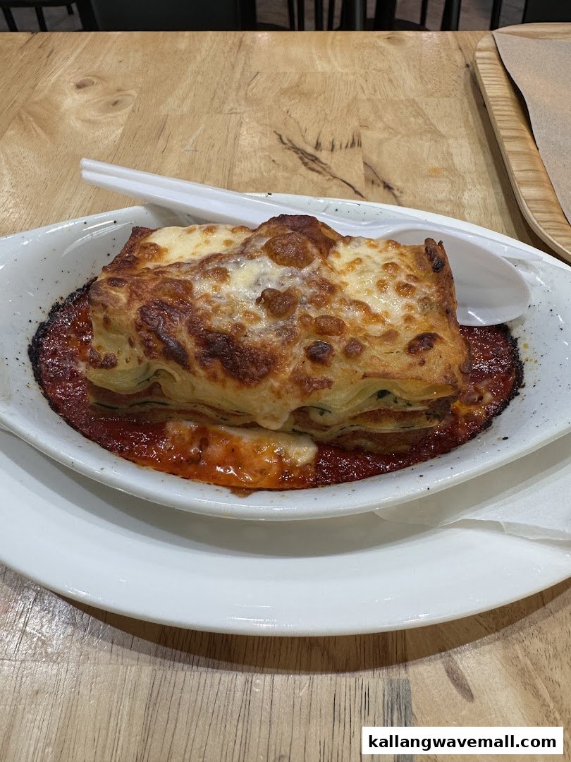 A delicious, cheesy baked lasagna dish served in a white bowl on a wooden table.