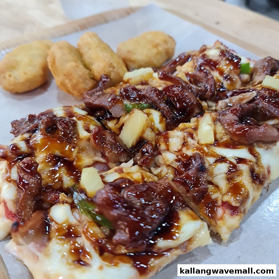 Close-up of gourmet pizza slices with meat, pineapple, and sauce, served with side nuggets.