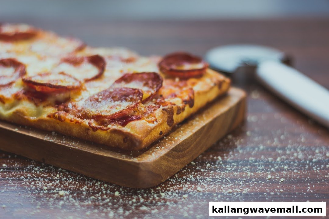 A rectangular pepperoni pizza slice on a wooden board with a pizza cutter.