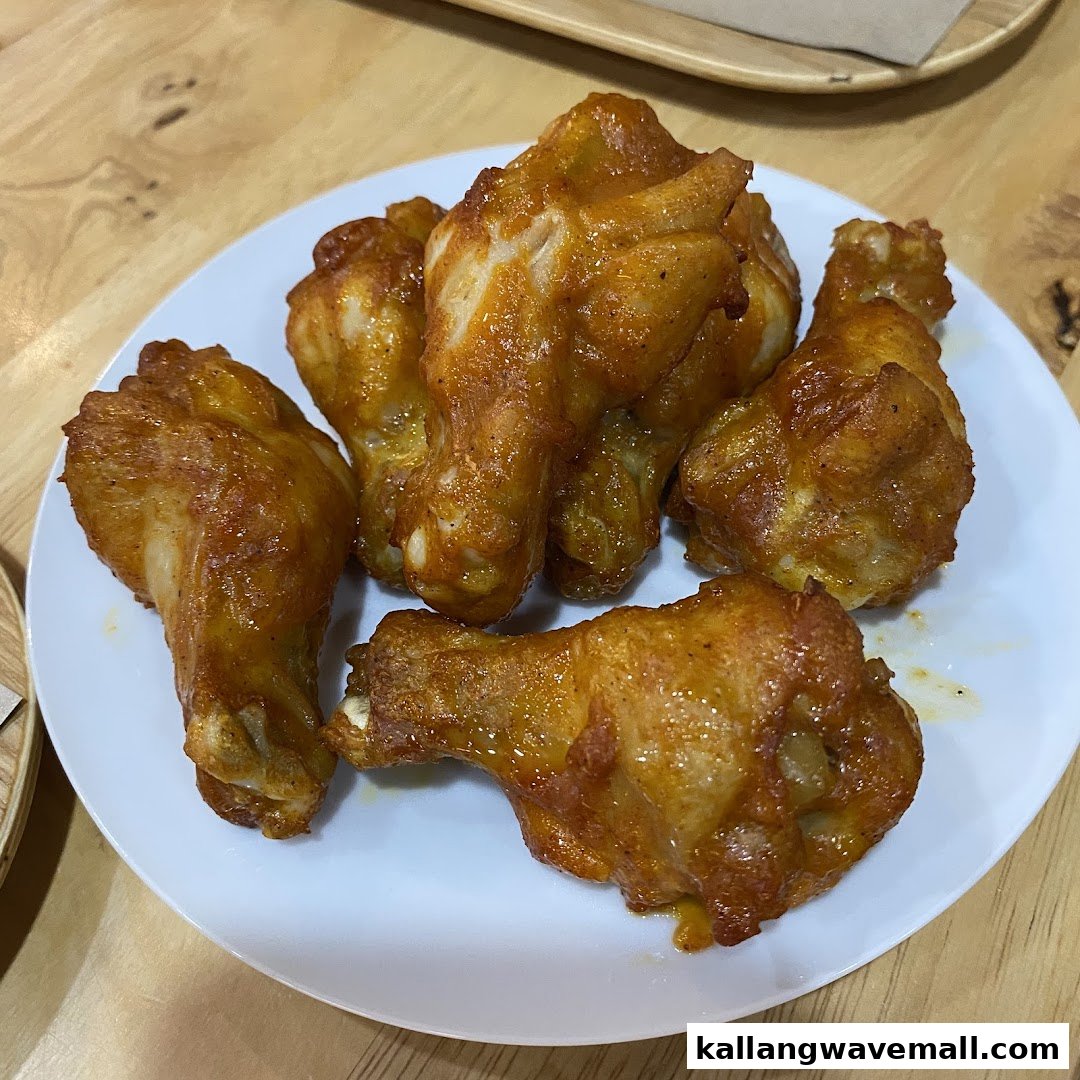 A plate of golden-brown, saucy chicken wings on a white plate.