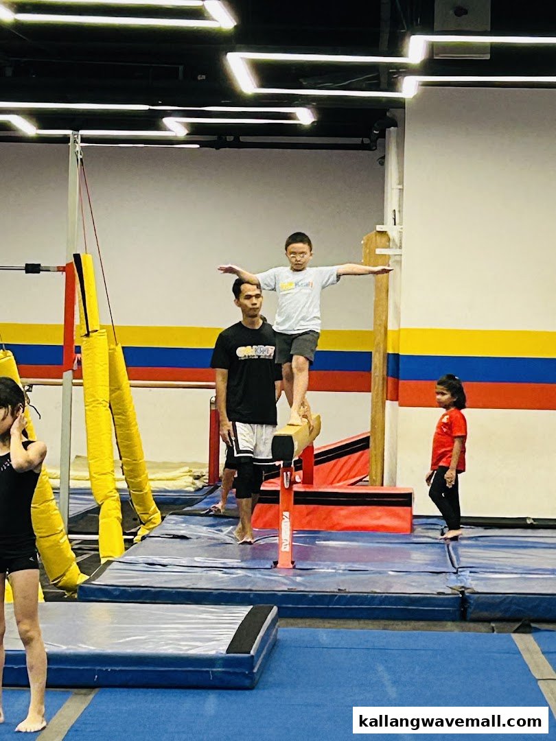 A child practices balancing on a gymnastics beam with an instructor at GymKraft.