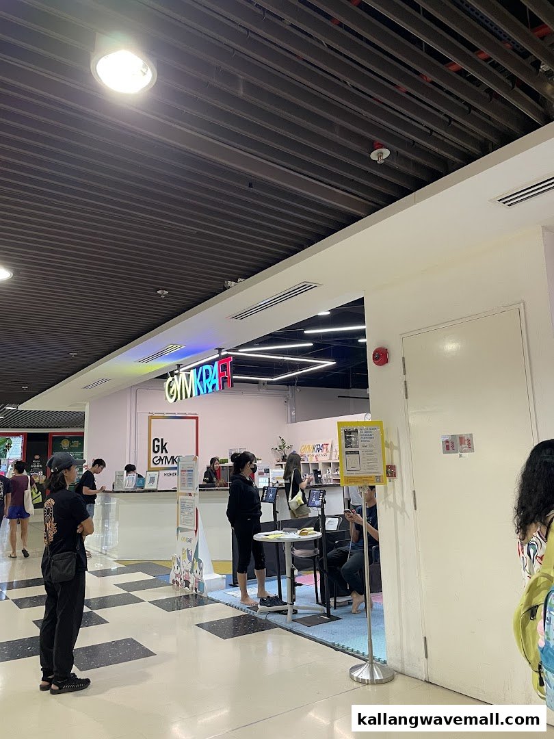 The entrance of GymKraft, a fitness center, with a reception desk and people.