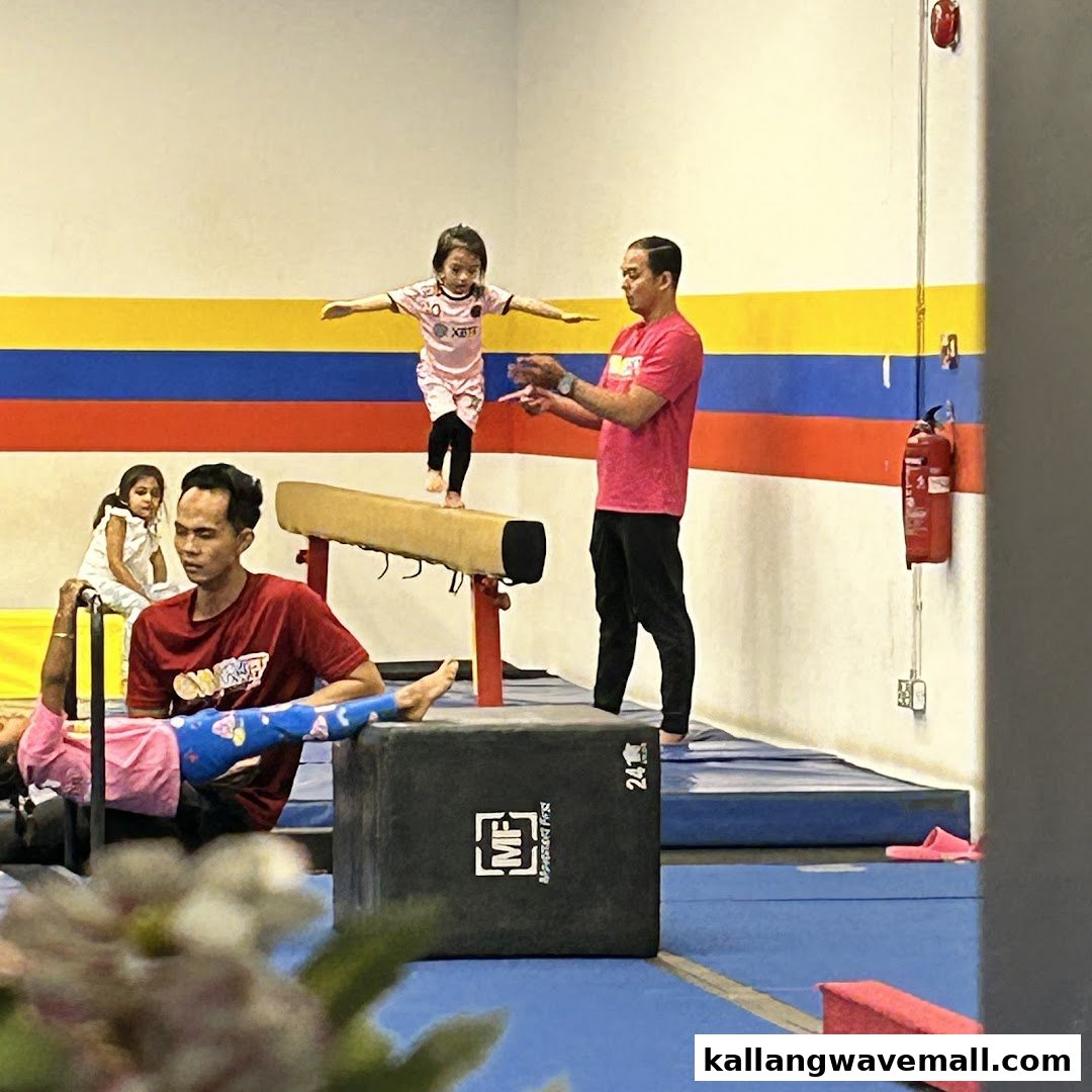 Children and instructors engaged in gymnastics training on a balance beam and mats at GymKraft.
