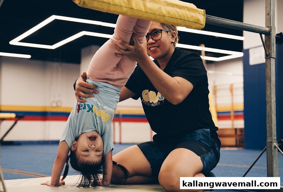 An instructor helps a young child practice a handstand at GymKraft, fostering fun and active learning.