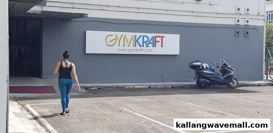 A person approaches the entrance of GymKraft, a fitness center, with its colorful sign prominently displayed.
