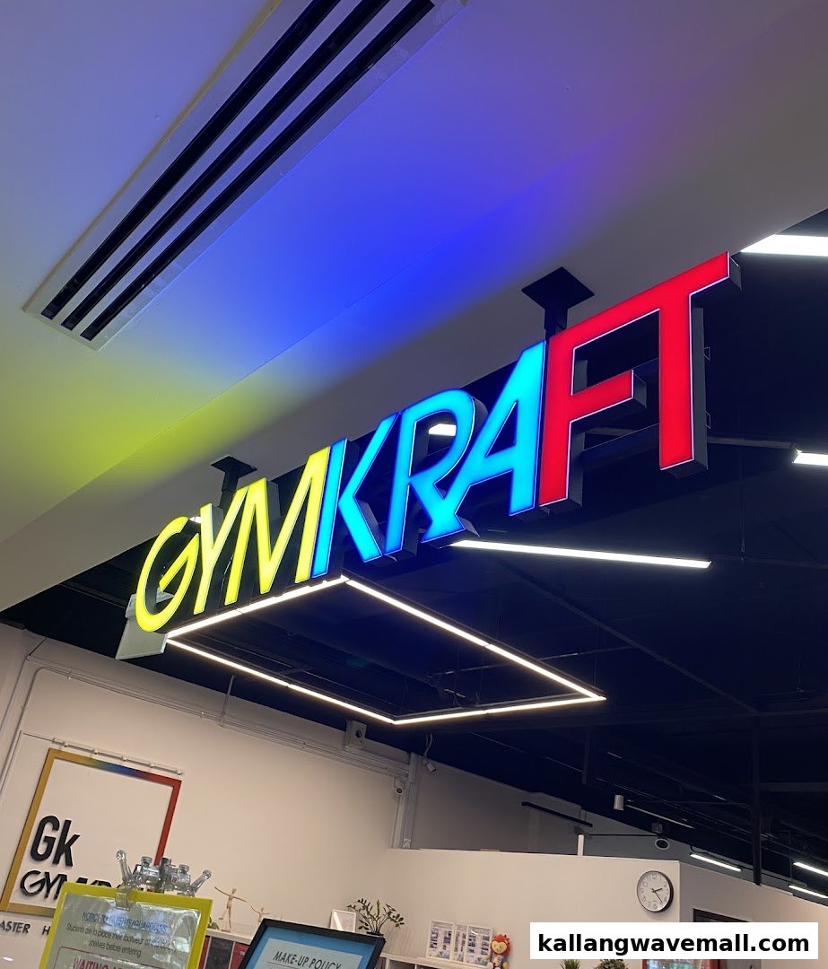 A vibrant, colorful 'GymKraft' sign illuminates the interior of the fitness facility.