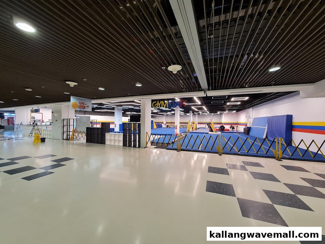 An interior view of GymKraft, a spacious gymnastics and fitness facility with blue mats and equipment.