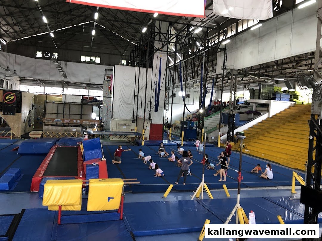 An expansive indoor gym with various training areas, including gymnastics mats, climbing walls, and aerial silks.