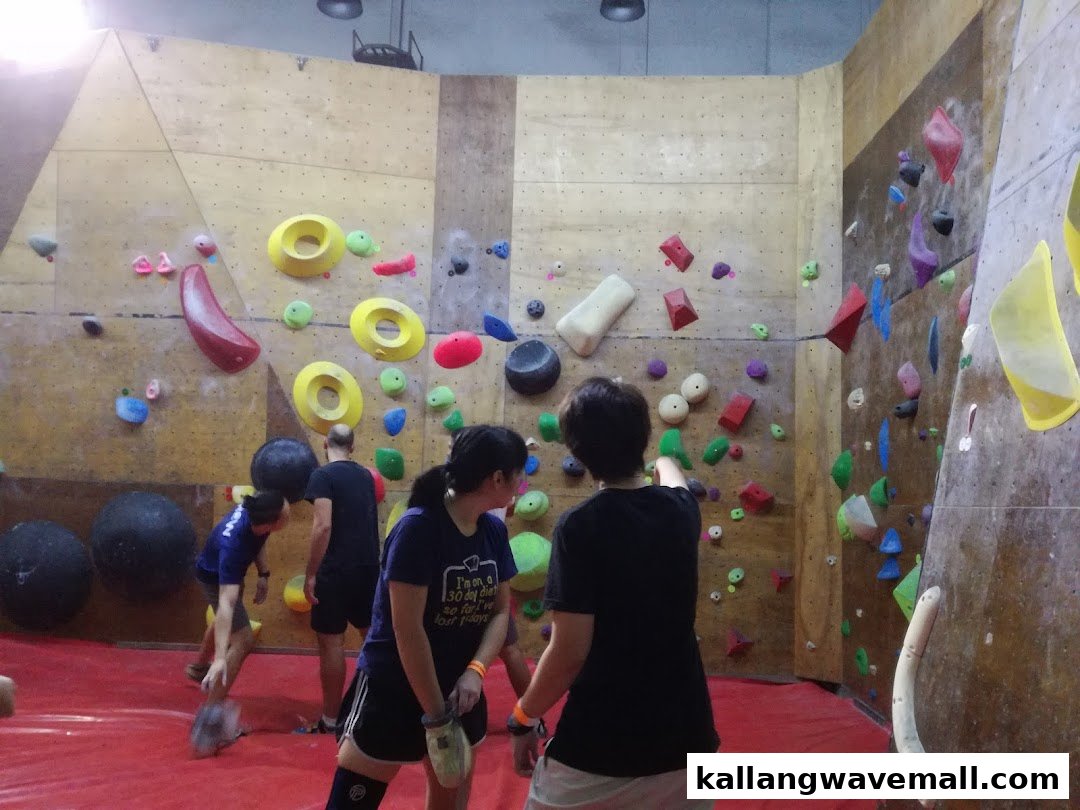 People bouldering on colorful climbing walls at GymKraft, an indoor climbing gym.