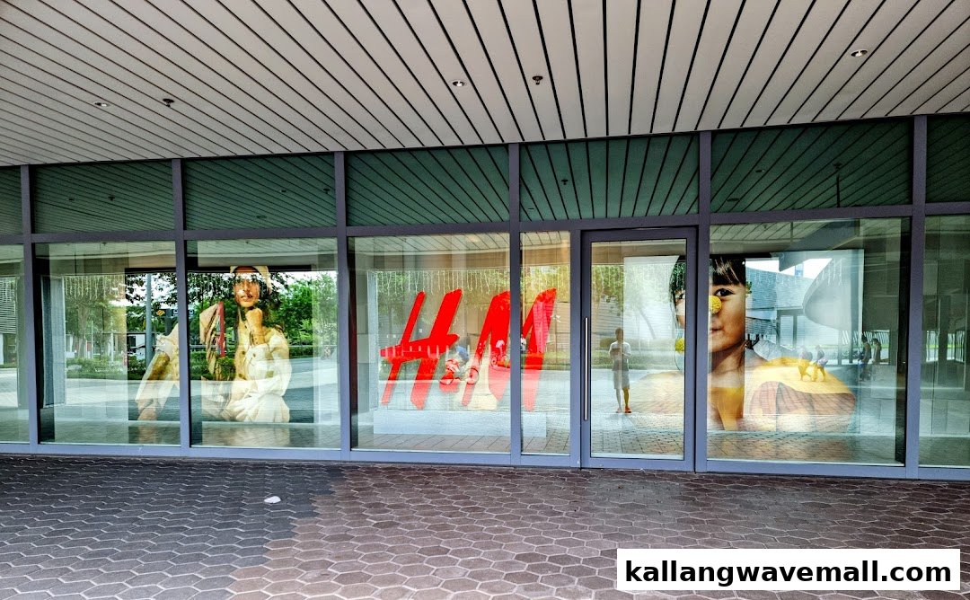 The H&M store entrance features large glass windows displaying the brand logo and promotional imagery.