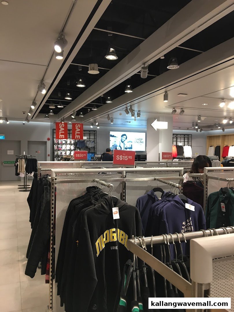 Interior view of an H&M store featuring clothing racks, sale signs, and a digital display.