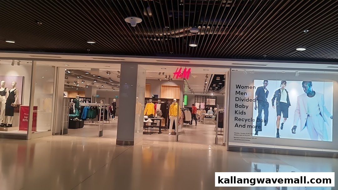 The brightly lit entrance of an H&M fashion store, showcasing clothing displays and a large digital advertisement.