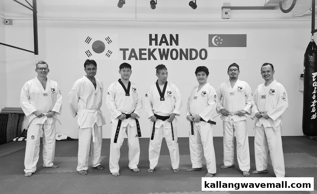 A group of instructors and students in Taekwondo uniforms posing inside the HAN Taekwondo studio.