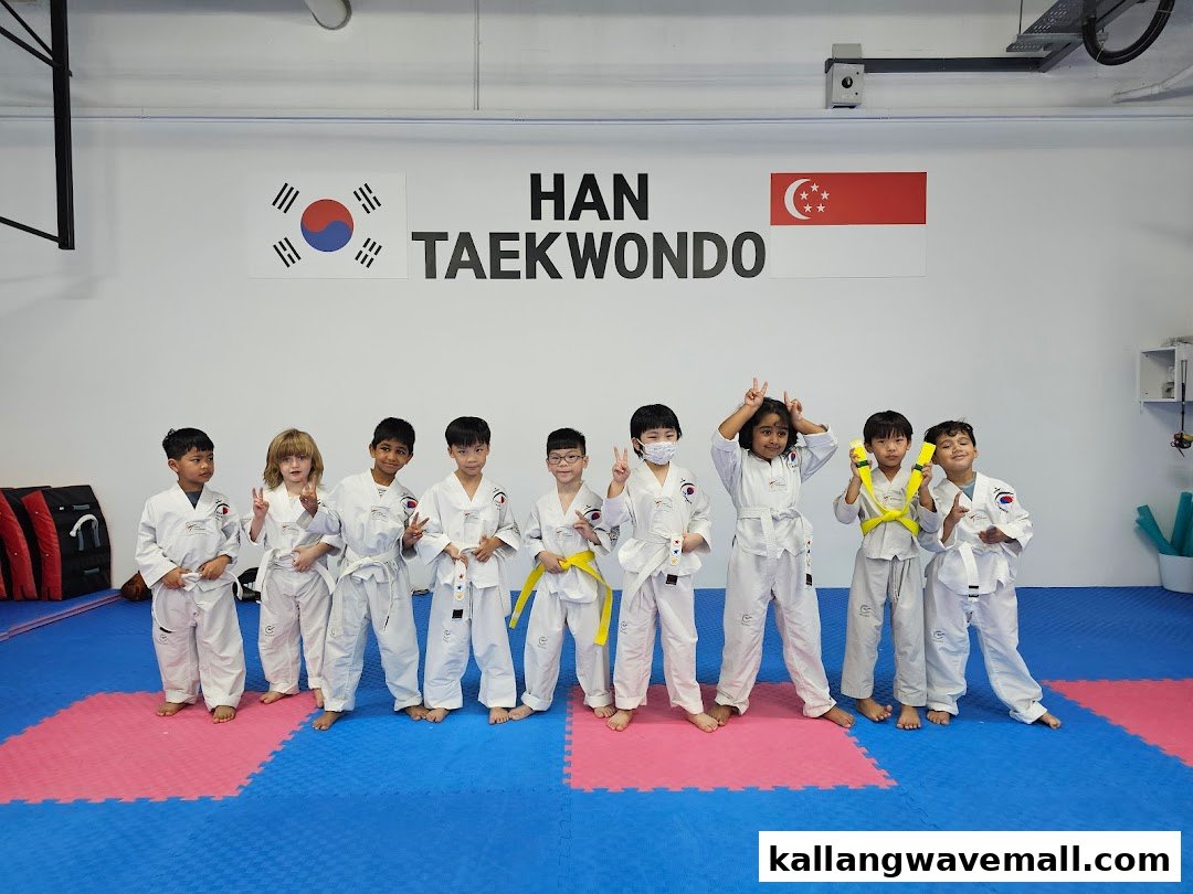 A group of children in white uniforms posing in a Taekwondo studio.