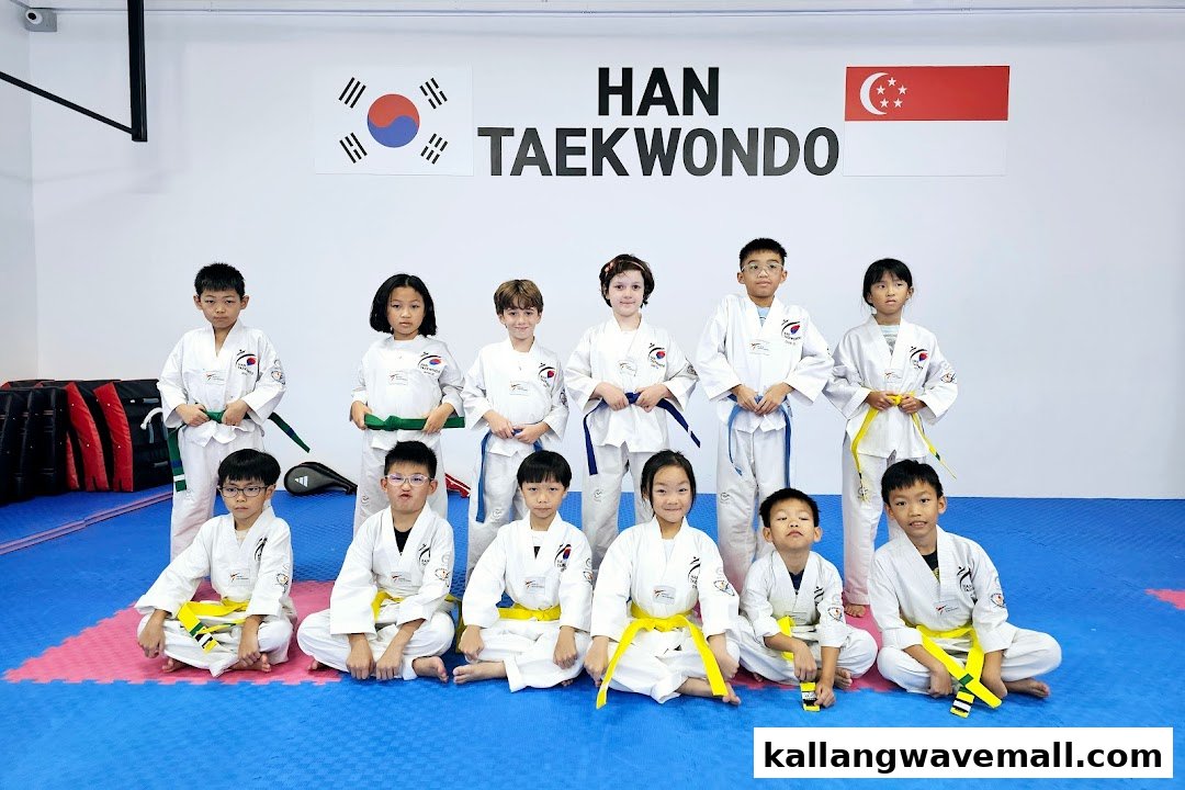 A group of children in white Taekwondo uniforms with colored belts posing in a studio.