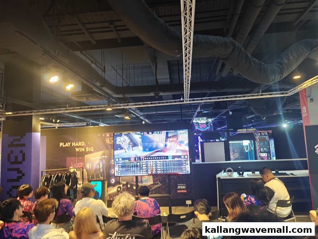 People gather to watch an esports match on a large screen inside a gaming cafe.