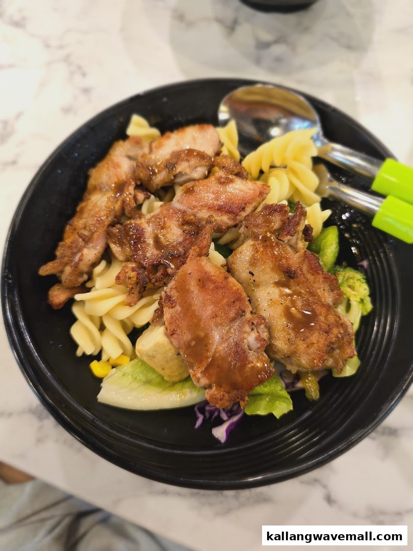 A vibrant bowl featuring grilled chicken, pasta, and fresh salad greens, served on a marble-patterned table.
