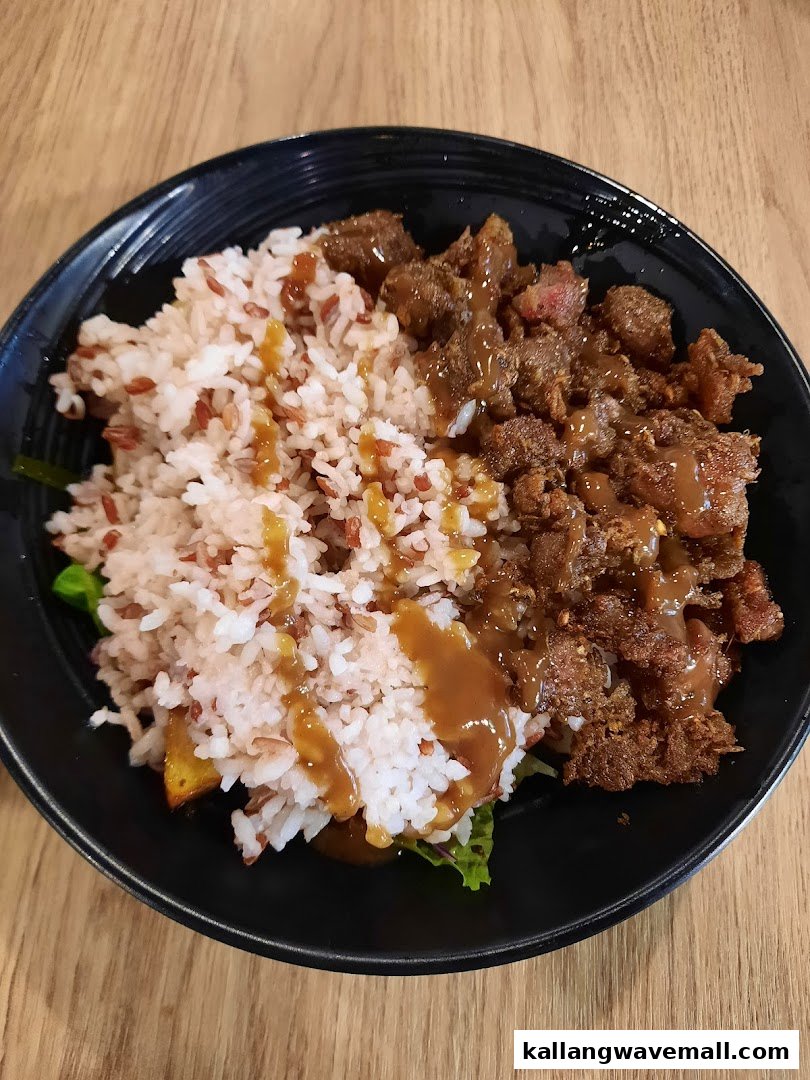 A close-up of a healthy food bowl featuring rice, meat, and a savory sauce.