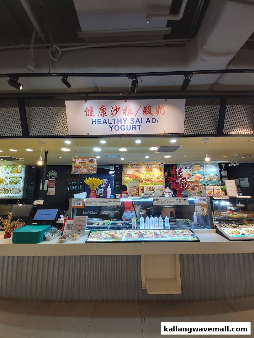 A vibrant food stall counter featuring fresh salads and yogurt, with a prominent 'Healthy Salad / Yogurt' sign.