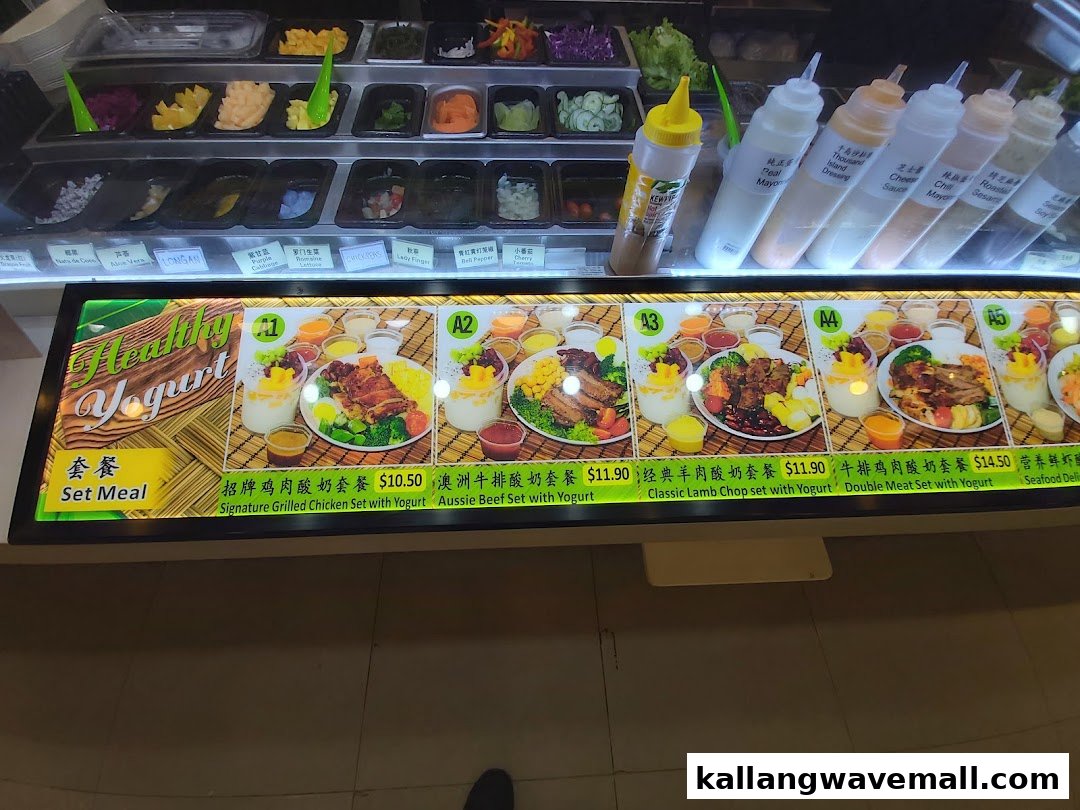 A vibrant food counter displaying fresh salad ingredients and a menu board with healthy set meals.