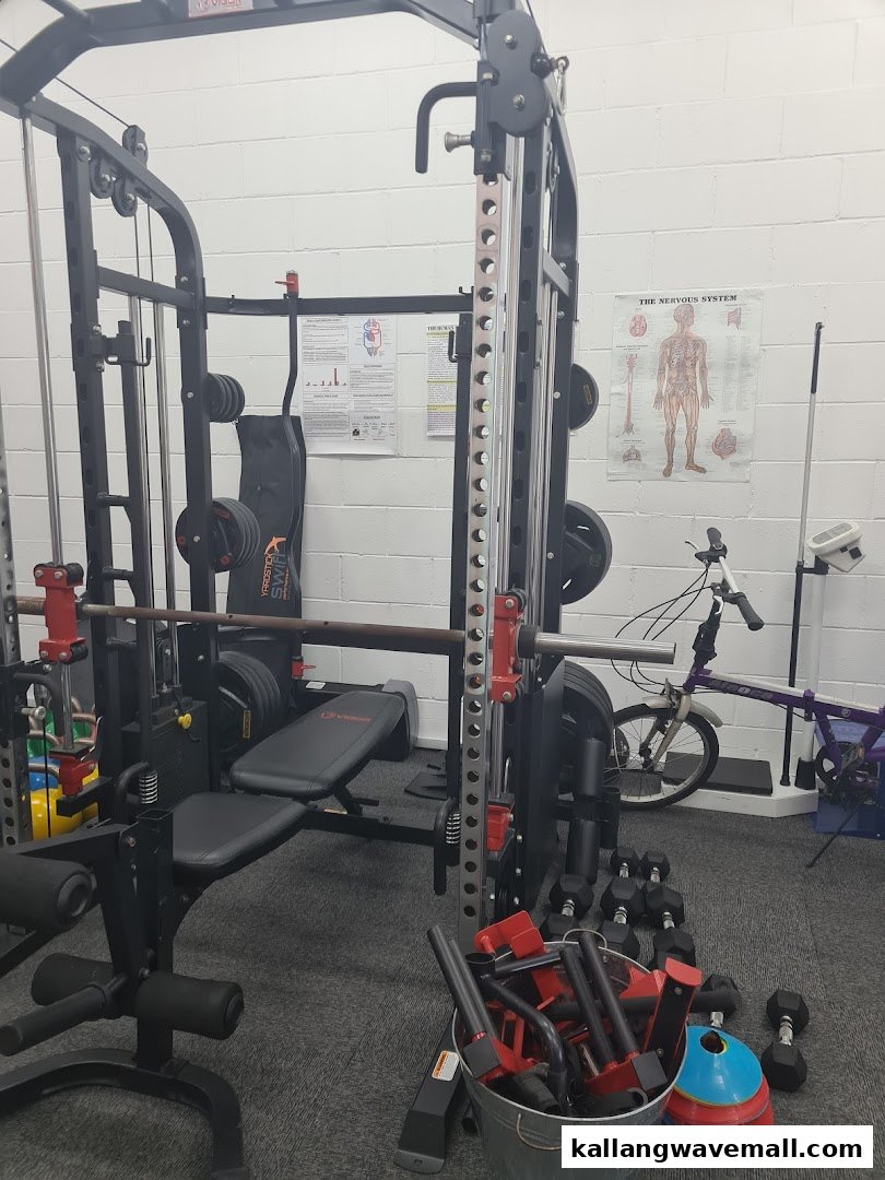 An interior view of a gym with weightlifting equipment, dumbbells, and fitness accessories.