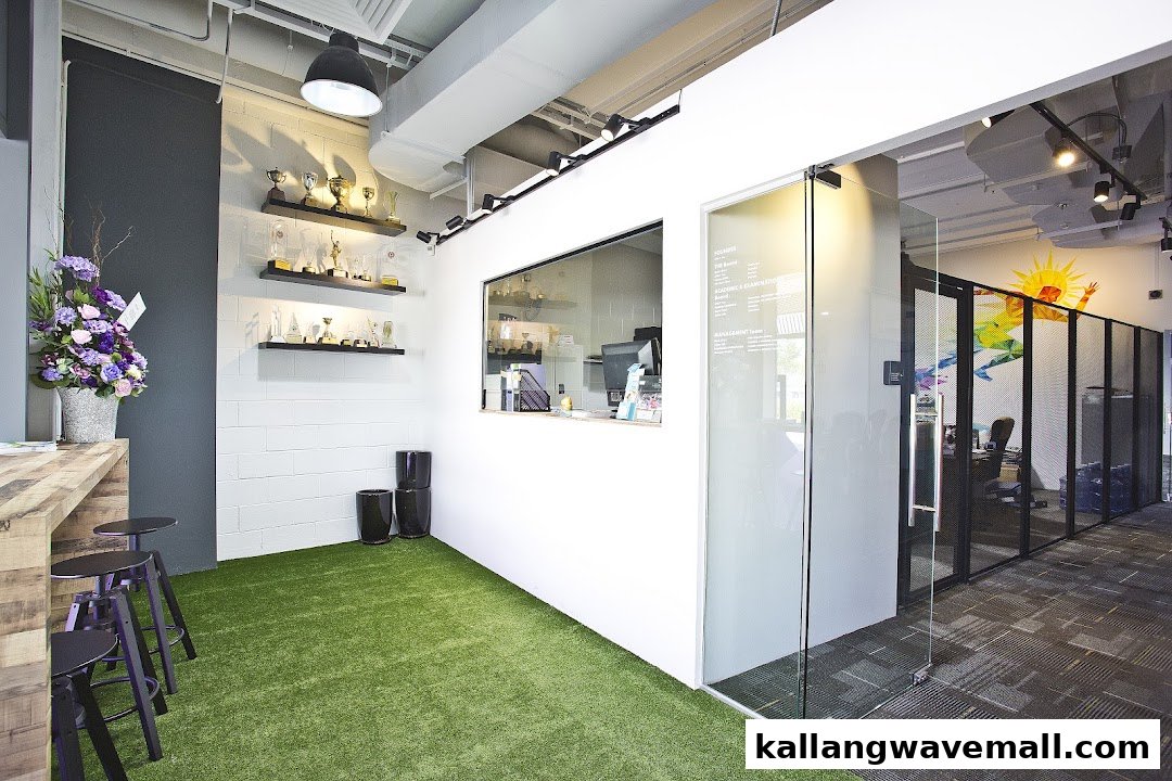 A modern sports academy interior featuring artificial turf, trophy display, and a reception area.