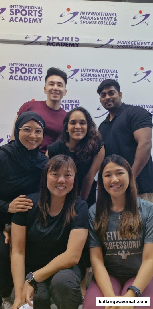 A diverse group of smiling individuals in front of the International Sports Academy branded wall.