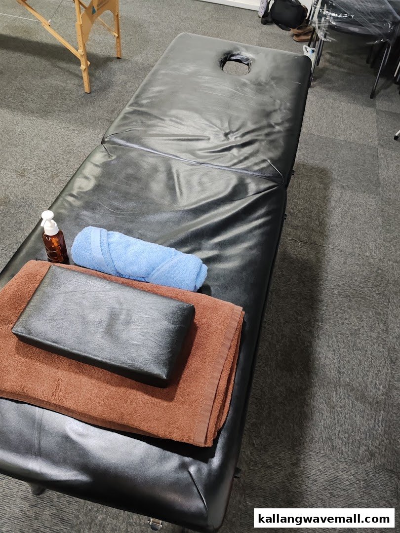 A black treatment table with towels and lotion, ready for therapy or recovery.